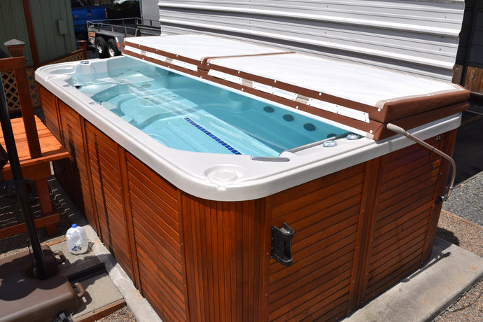 Swim spa with a three panel cinnamon cover and lifter